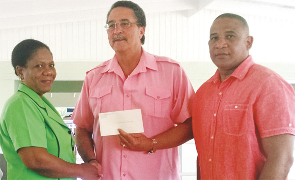 Mrs Gustave receives the cheque from Prime Minister Anthony. High Commissioner Hilaire is at right.