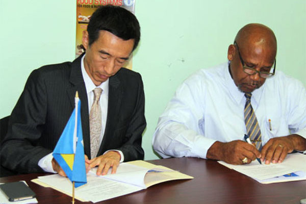 Image: Ambassador Mou and Minister Joseph sign the action plan.