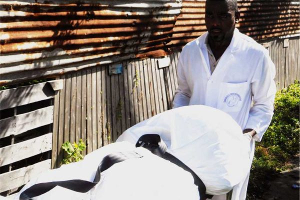 Image of Rambally Funeral Parlour staff removing one of the bodies.