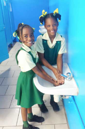 Image of Two students of the Balata Government School as they completing a visit to the newly refurbished bathroom the right way.
