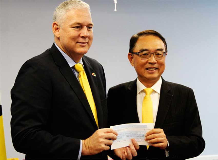 Image of Prime Minister Allen Chastanet accepting a cheque for EC$180,000 from Taiwanese Ambassador to St. Lucia, Douglas Shen