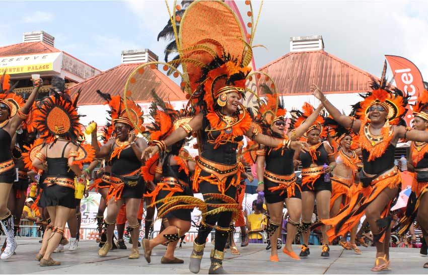 Carnival revellers dancing around in their orange and black costumes.