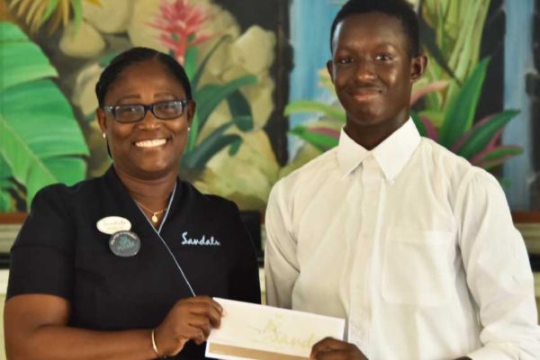 Image: Shaquil Flavius receiving his scholarship pack from Versilia Jn Baptiste, Front Office Supervisor, Sandals Halcyon Beach Resort.