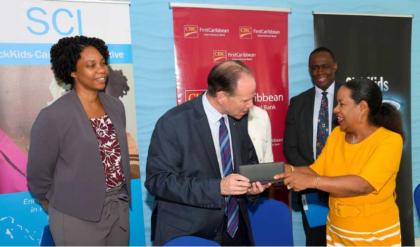 Image: Debra King, Director of Corporate Communications, CIBC FirstCaribbean presenting CEO of SickKids Foundation Ted Garrard with the pens used in the signing ceremony. Looking on is SickKids Fellow Dr Chantelle Browne-Farmer (back left) Bonnie Fleming-Caro (partly hidden), Associate Chief of Nursing & Inter-professional Education at SickKids (centre) and Dr Upton Allen, Chief of the Division of Infectious Diseases at SickKids.