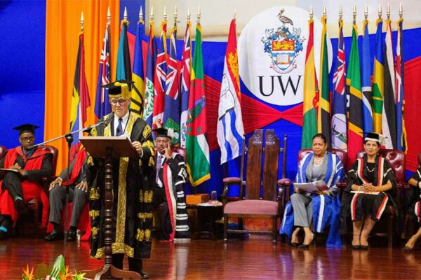 Image: Chancellor Robert Bermudez addressing the company as members of the UWI Executive on the platform look on.