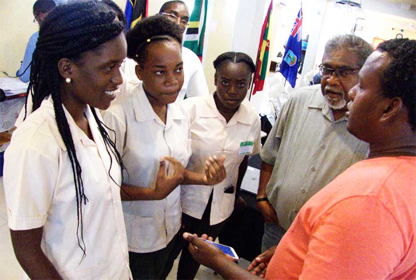 Image of Farmer Garvey Charlemagne demonstrating ICTs on mobile phone to SALCC students, Lecturer and project trainer.