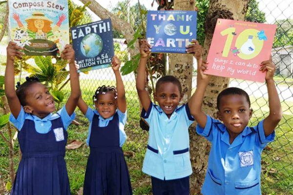 Image of Students at Moneague Teachers’ College Basic School in Jamaica, share bright smiles after taking part in a reading session with environmental books.