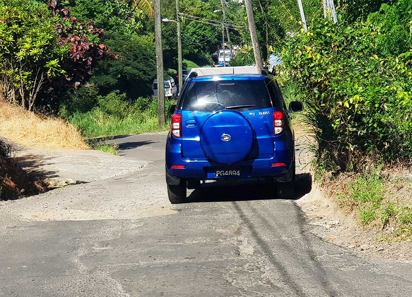 Image of a vehicles retreating to the opposite side of the road to avoid mammoth pothole.