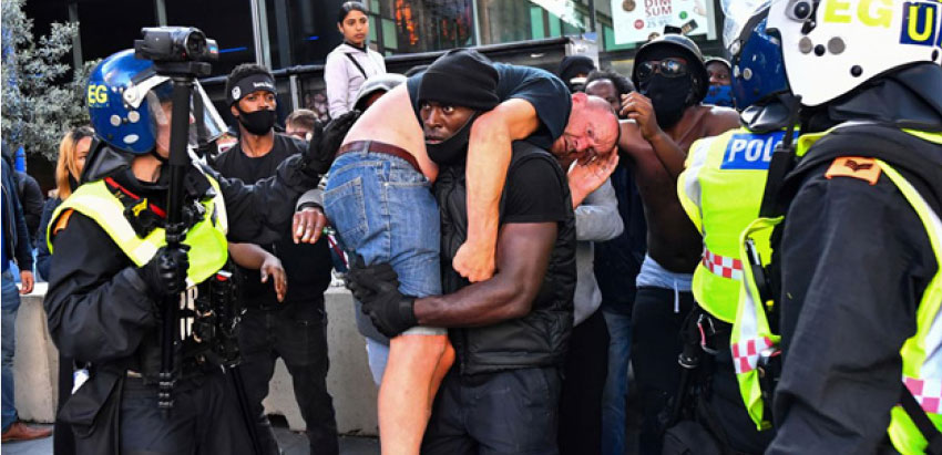 Image of protestor Patrick Hutchinson (centre) carries off an injured white man on his shoulder during a violent scuffle at a protest in London against the murder of George Floyd. Photo Credit: Dylan Martinez/Reuters. 