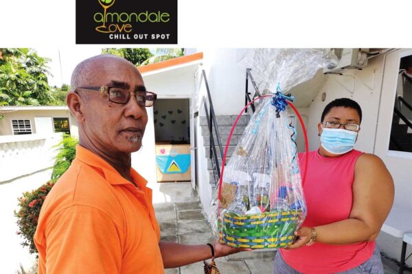 Ishmael handing over to The Children's Montessori House a basket load of items manufactured to help protect the children and staff of the pre-school against COVID-19. Receiving on behalf of the pre-school is Mrs. Deon Joseph