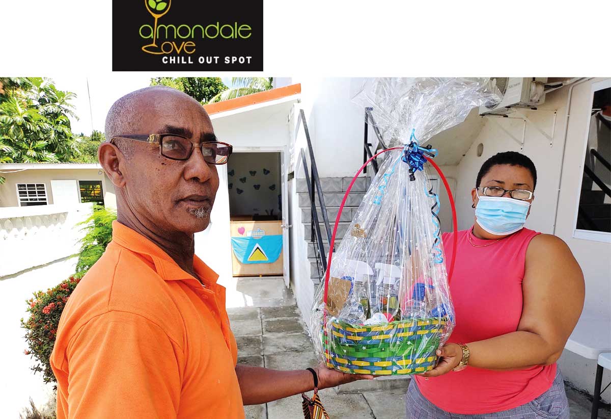 Ishmael handing over to The Children's Montessori House a basket load of items manufactured to help protect the children and staff of the pre-school against COVID-19.  Receiving on behalf of the pre-school is Mrs. Deon  Joseph 