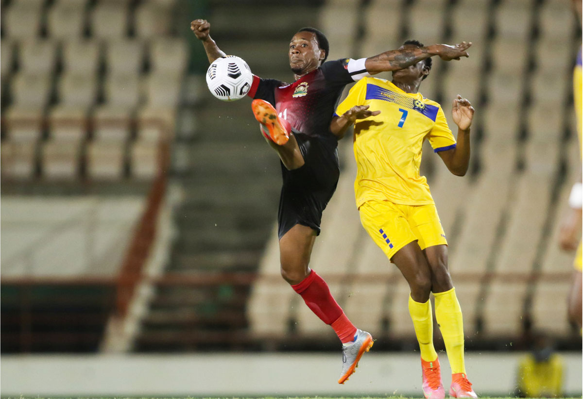 An Antiguan player (red and black) fights for possession of the ball with a Bajan opponent …