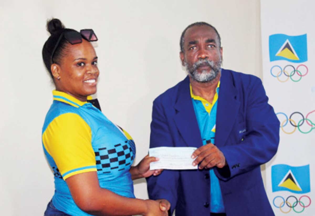 Kerin Neptune, senior volleyball player, left, accepting the cheque on her association’s behalf from SLOC Inc’s President, Alfred Emmanuel.