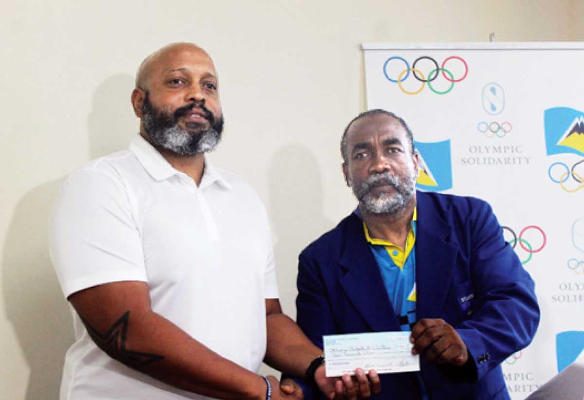 Leslie Collymore, President of the Saint Lucia Basketball Federation, left, accepting the cheque on his association’s behalf from SLOC Inc’s President, Alfred Emmanuel.
