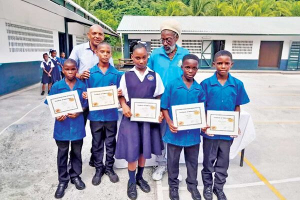Stephen Joseph (left) and Physical Education [PE] Teacher Chester Corsinie pose with students as they display their ‘Bronze Award’ certificates
