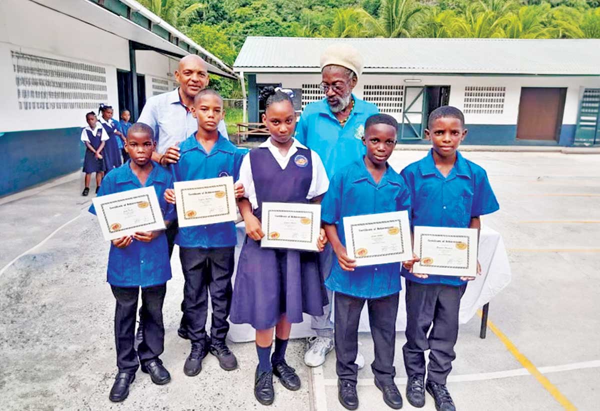 Stephen Joseph (left) and Physical Education [PE] Teacher Chester Corsinie pose with students as they display their ‘Bronze Award’ certificates
