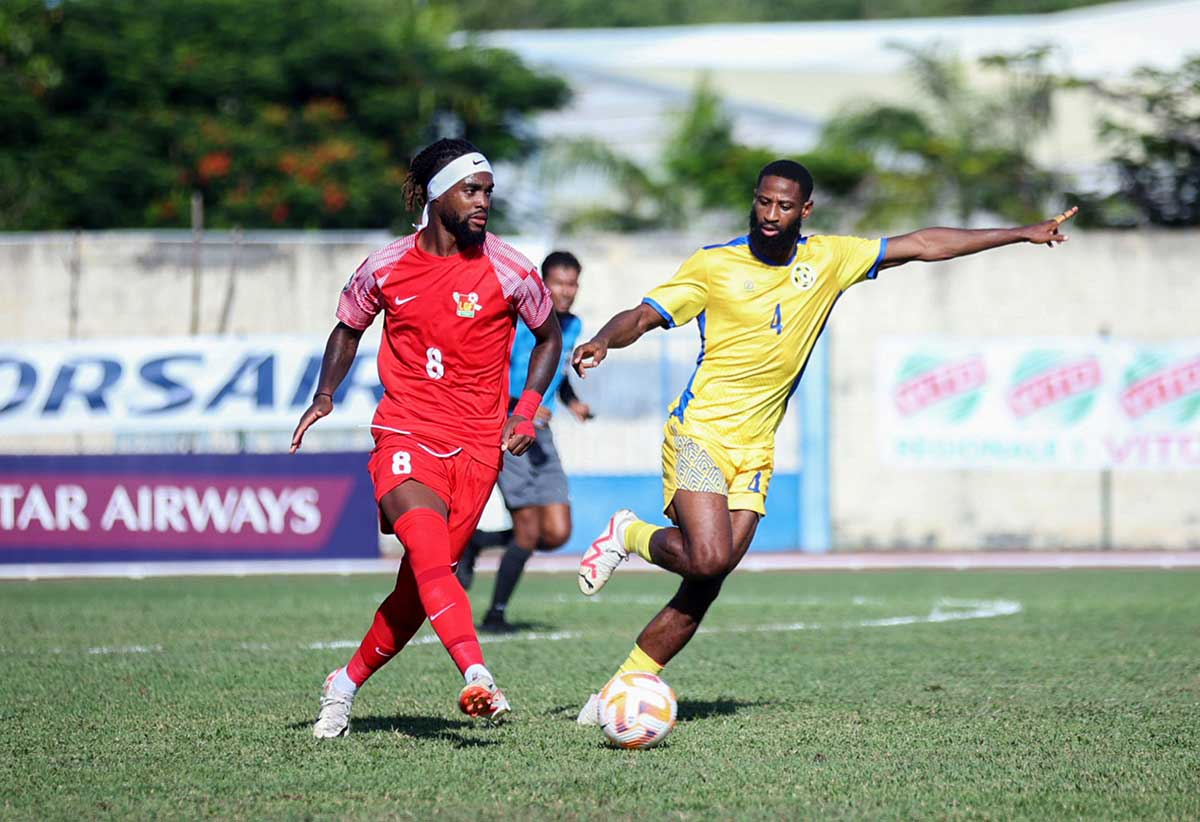 A Guadeloupian striker (red outfit) takes on Team Saint Lucia’s defense 