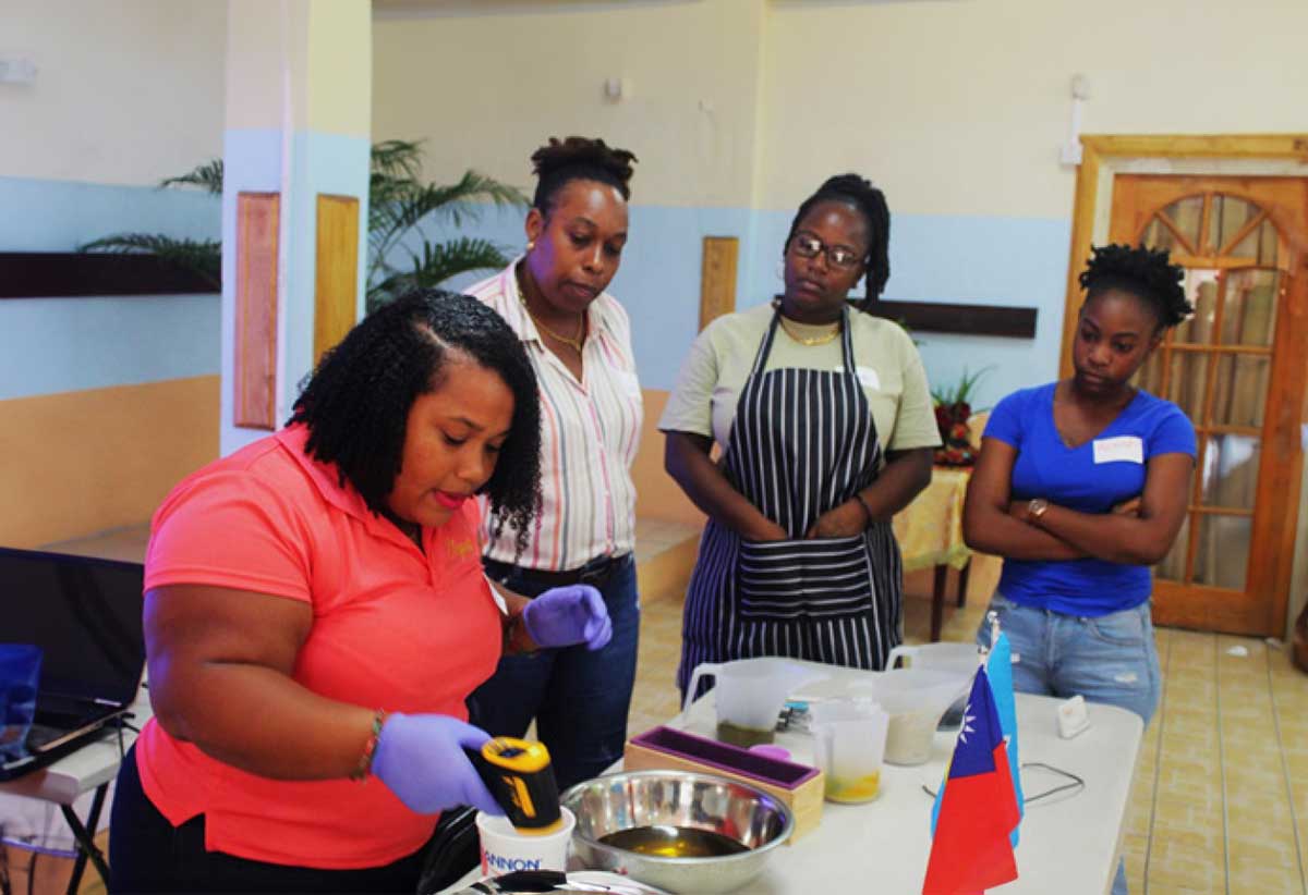 Facilitator Kishma Louis (far left )demonstrating to participants how to mix ingredients in the soap-making process. 